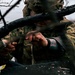 Soldier Prepares Munition Among Charred Trees in Forward Position