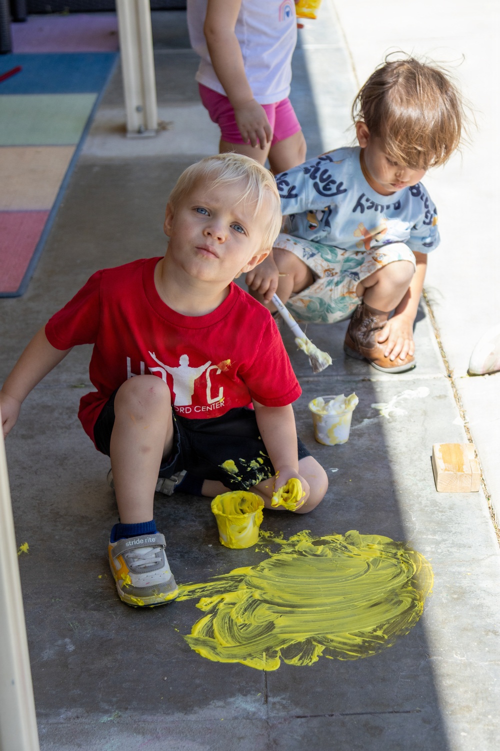 Children engage in outdoor painting activity for Earth Day event at the child development center
