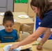 Liz Barron assists child during Earth Day event aboard Child development Center