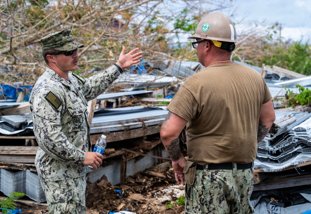U.S. Sailors and U.S. Soldiers load lumber and ridge caps onto trucks