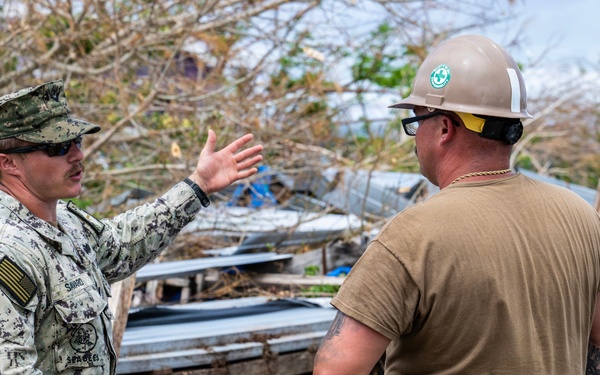 U.S. Sailors and U.S. Soldiers load lumber and ridge caps onto trucks