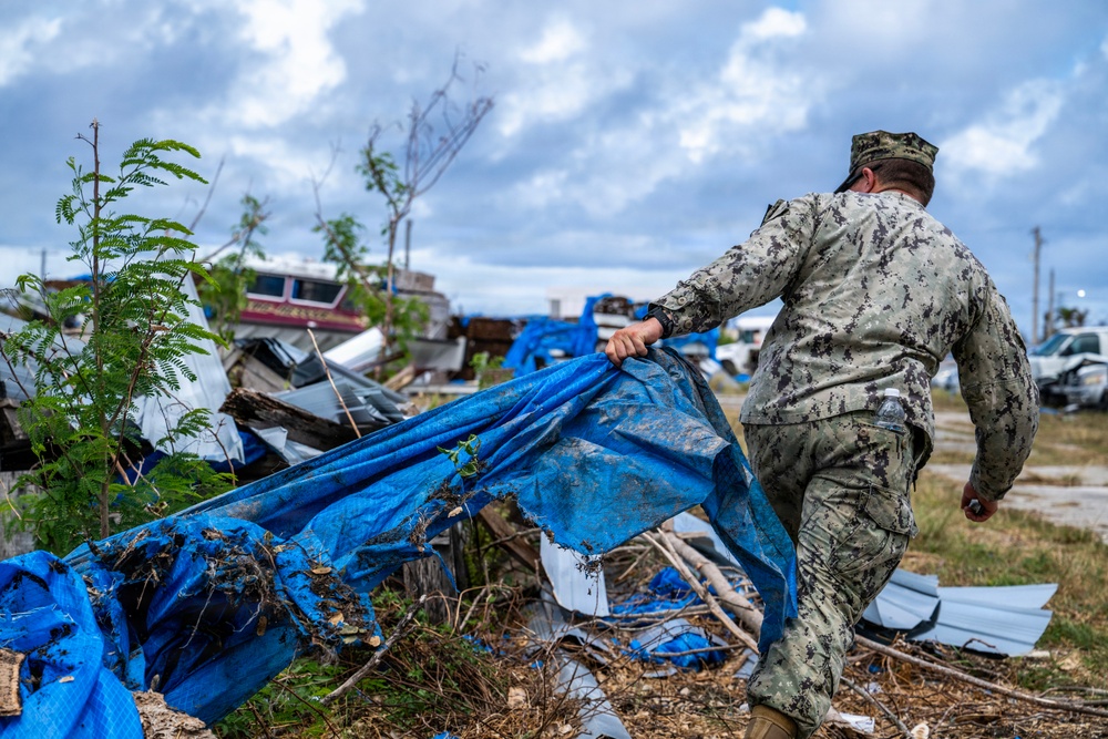 U.S. Sailors and U.S. Soldiers load lumber and ridge caps onto trucks