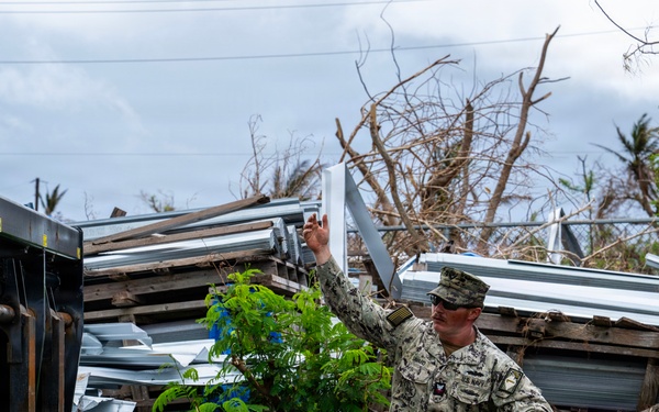U.S. Sailors and U.S. Soldiers load lumber and ridge caps onto trucks
