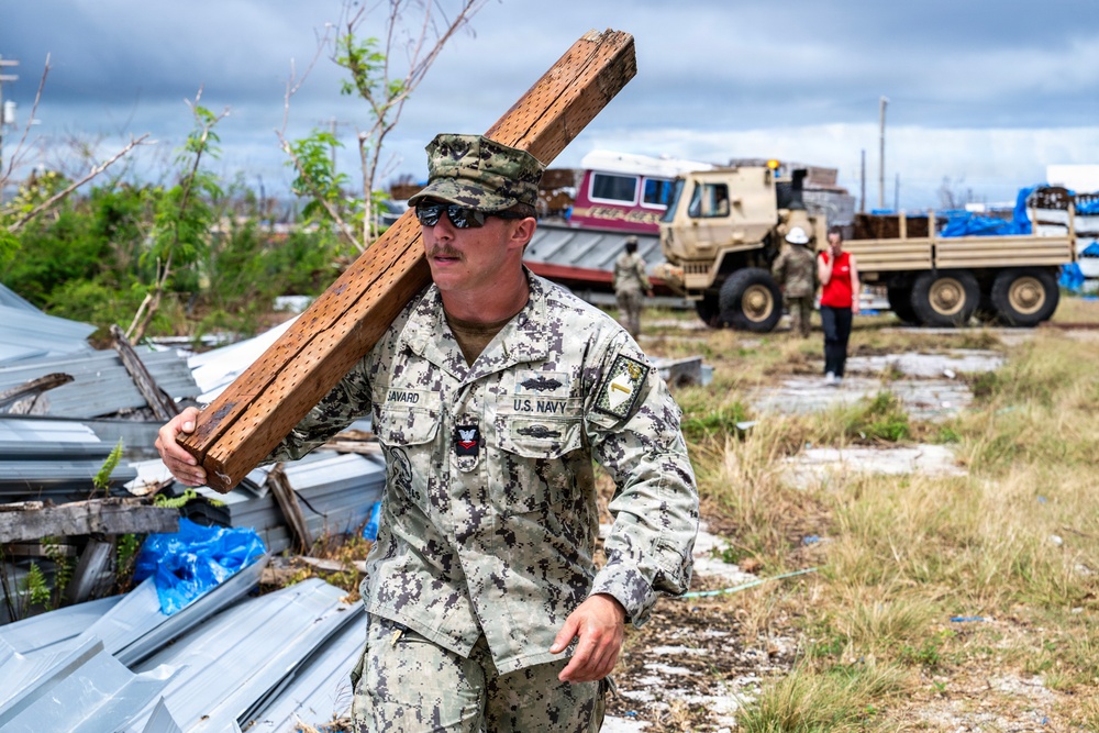 U.S. Sailors and U.S. Soldiers load lumber and ridge caps onto trucks