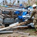 U.S. Sailors and U.S. Soldiers load lumber and ridge caps onto trucks