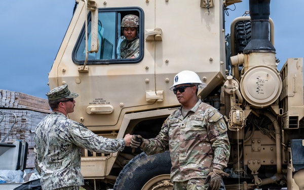 U.S. Sailors and U.S. Soldiers load lumber and ridge caps onto trucks