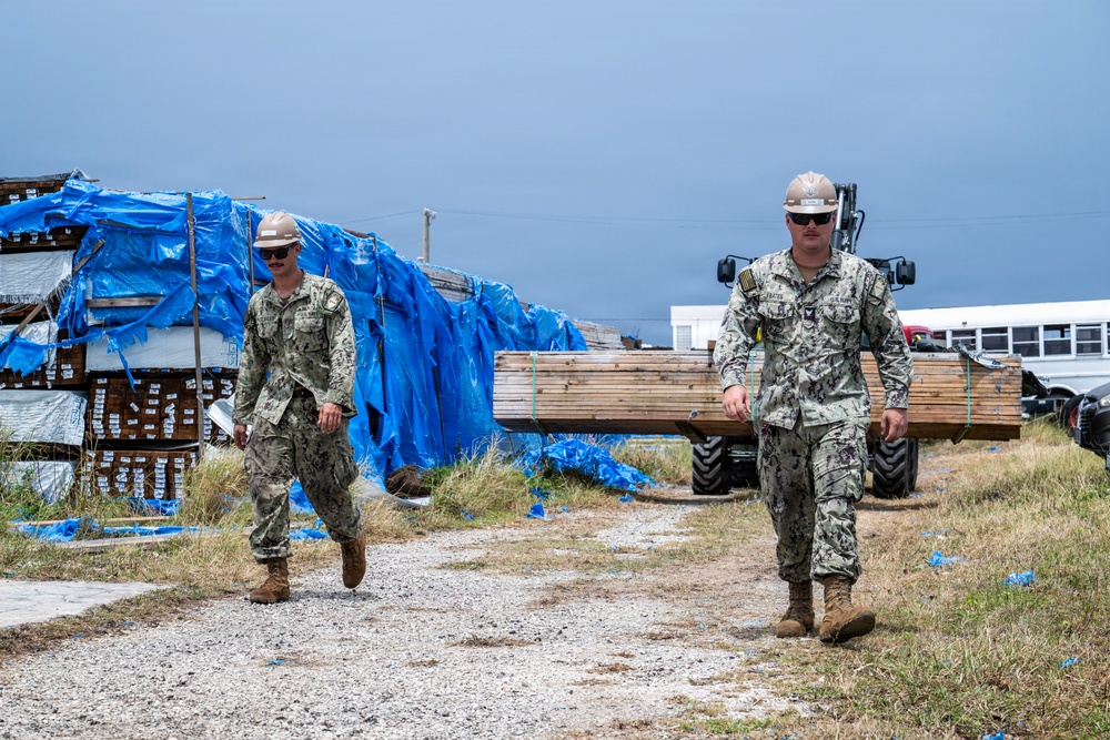 U.S. Sailors and U.S. Soldiers load lumber and ridge caps onto trucks