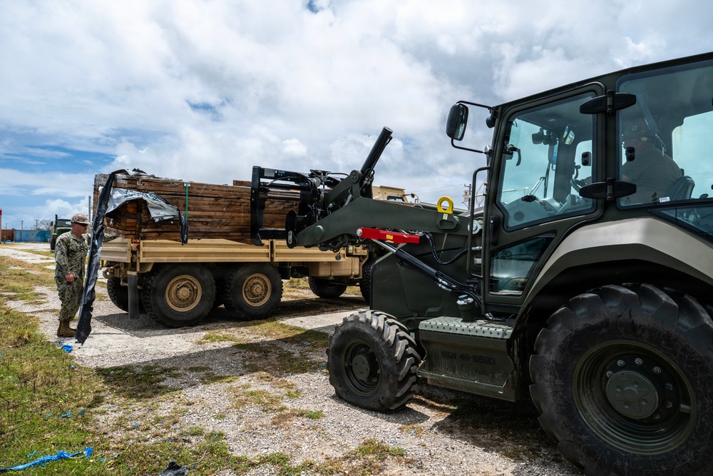 U.S. Sailors and U.S. Soldiers load lumber and ridge caps onto trucks