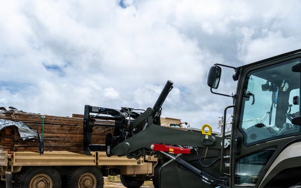 U.S. Sailors and U.S. Soldiers load lumber and ridge caps onto trucks