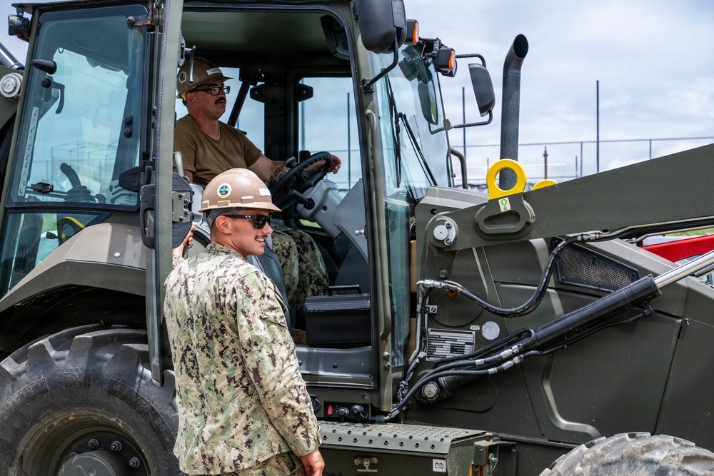 U.S. Sailors and U.S. Soldiers load lumber and ridge caps onto trucks