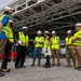 Military and civilian officials conduct construction site walkthrough of large steel-framed facility