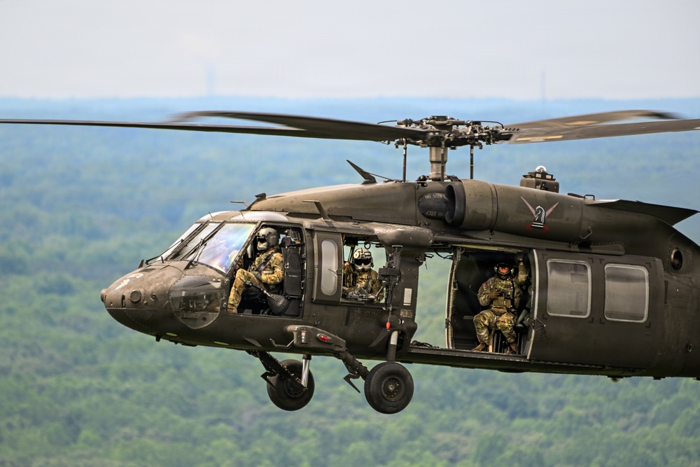 U.S. Army UH-60 Black Hawk helicopter crew conducts flight operations over wooded terrain