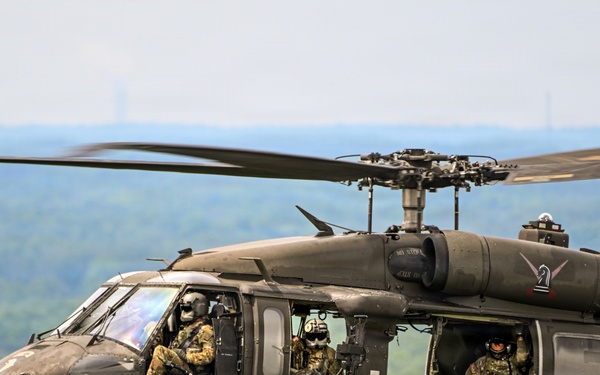 U.S. Army UH-60 Black Hawk helicopter crew conducts flight operations over wooded terrain