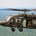 U.S. Army UH-60 Black Hawk helicopter crew conducts flight operations over wooded terrain