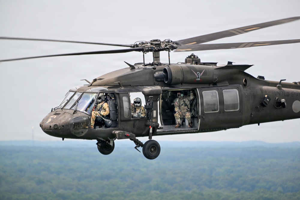 U.S. Army UH-60 Black Hawk helicopter conducts airborne operations over forested terrain