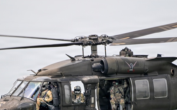 U.S. Army UH-60 Black Hawk helicopter conducts airborne operations over forested terrain