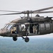 U.S. Army UH-60 Black Hawk helicopter conducts airborne operations over forested terrain