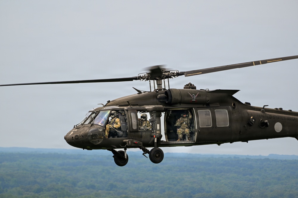 U.S. Army UH-60 Black Hawk helicopter crew conducts airborne operations over wooded terrain