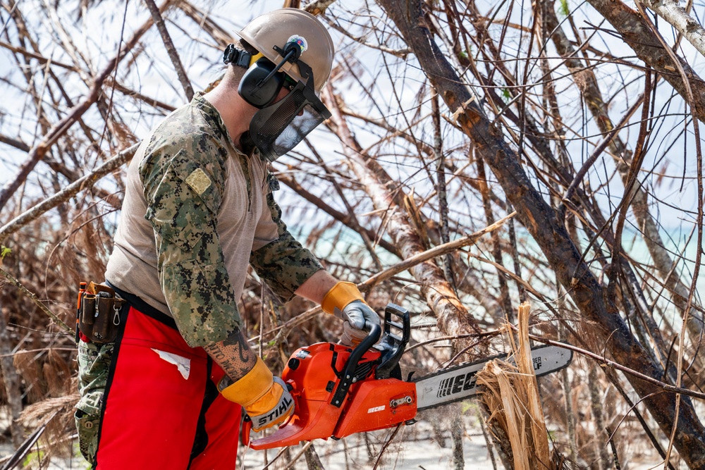 NMCB 1 Sailors clear an area with chainsaws and a backhoe