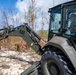 NMCB 1 Sailors clear an area with chainsaws and a backhoe
