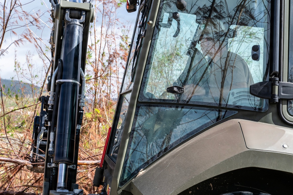 NMCB 1 Sailors clear an area with chainsaws and a backhoe