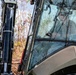 NMCB 1 Sailors clear an area with chainsaws and a backhoe
