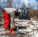NMCB 1 Sailors clear an area with chainsaws and a backhoe