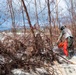 NMCB 1 Sailors clear an area with chainsaws and a backhoe