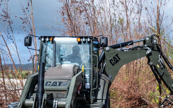 NMCB 1 Sailors clear an area with chainsaws and a backhoe