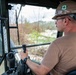 NMCB 1 Sailors clear an area with chainsaws and a backhoe