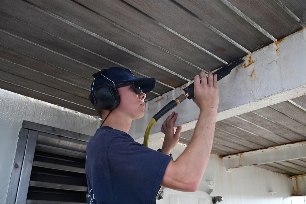 USCGC Eagle crew members and cadets prep the training barque for paint ahead of America 250 events