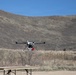 Quadcopter drone hovers during outdoor field test in arid terrain