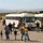 Visitors board white shuttle buses at a military installation open house event in a high desert setting