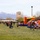 Military families gather for outdoor community event featuring inflatable bounce houses with snow-capped mountains in background