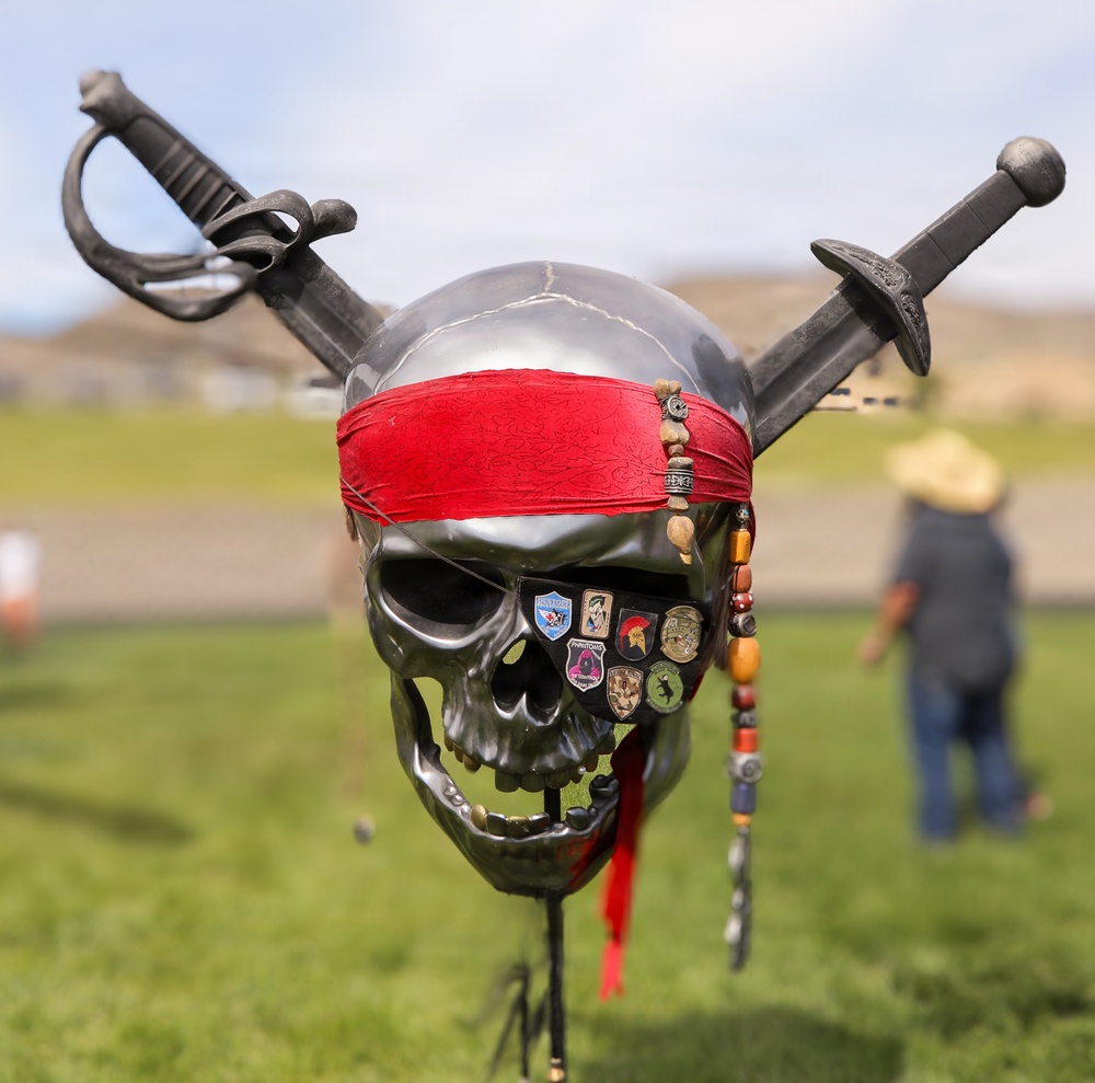 Pirate skull mascot adorned with military unit patches and crossed swords on display at outdoor event