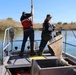 Two crew members netting fish near reed bank