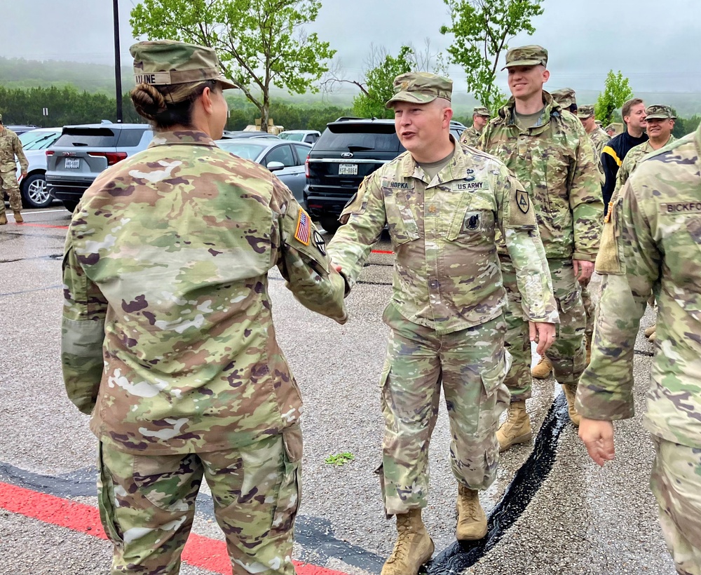 Fellow officer congratulates outgoing officer during farewell ceremony at West Fort Hood