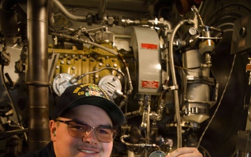 U.S. Navy Sailor displays challenge coin in ship's engine room