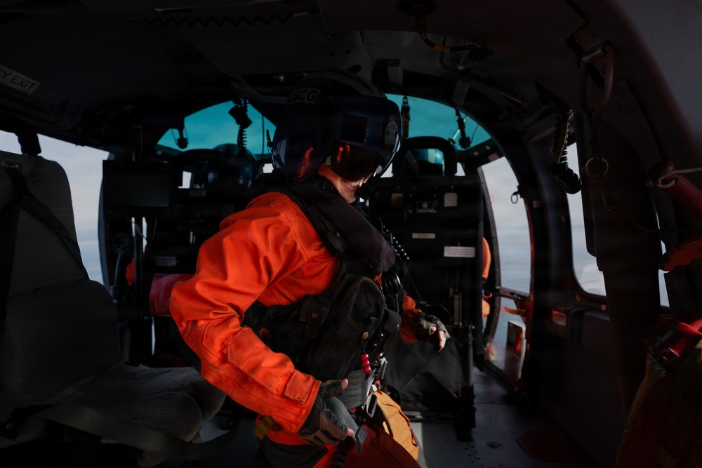 U.S. Coast Guard aircrew member prepares for flight operations aboard an MH-65 Dolphin helicopter.