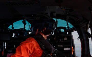 U.S. Coast Guard aircrew member prepares for flight operations aboard an MH-65 Dolphin helicopter.