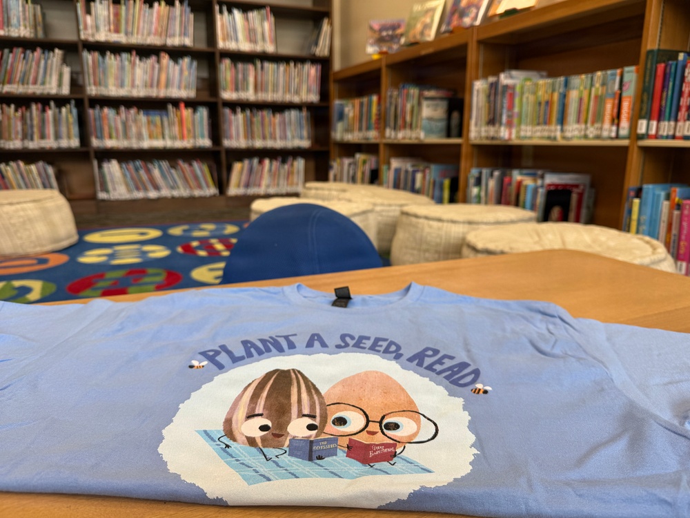 Plant A Seed Read literacy promotion T-shirt displayed in school library