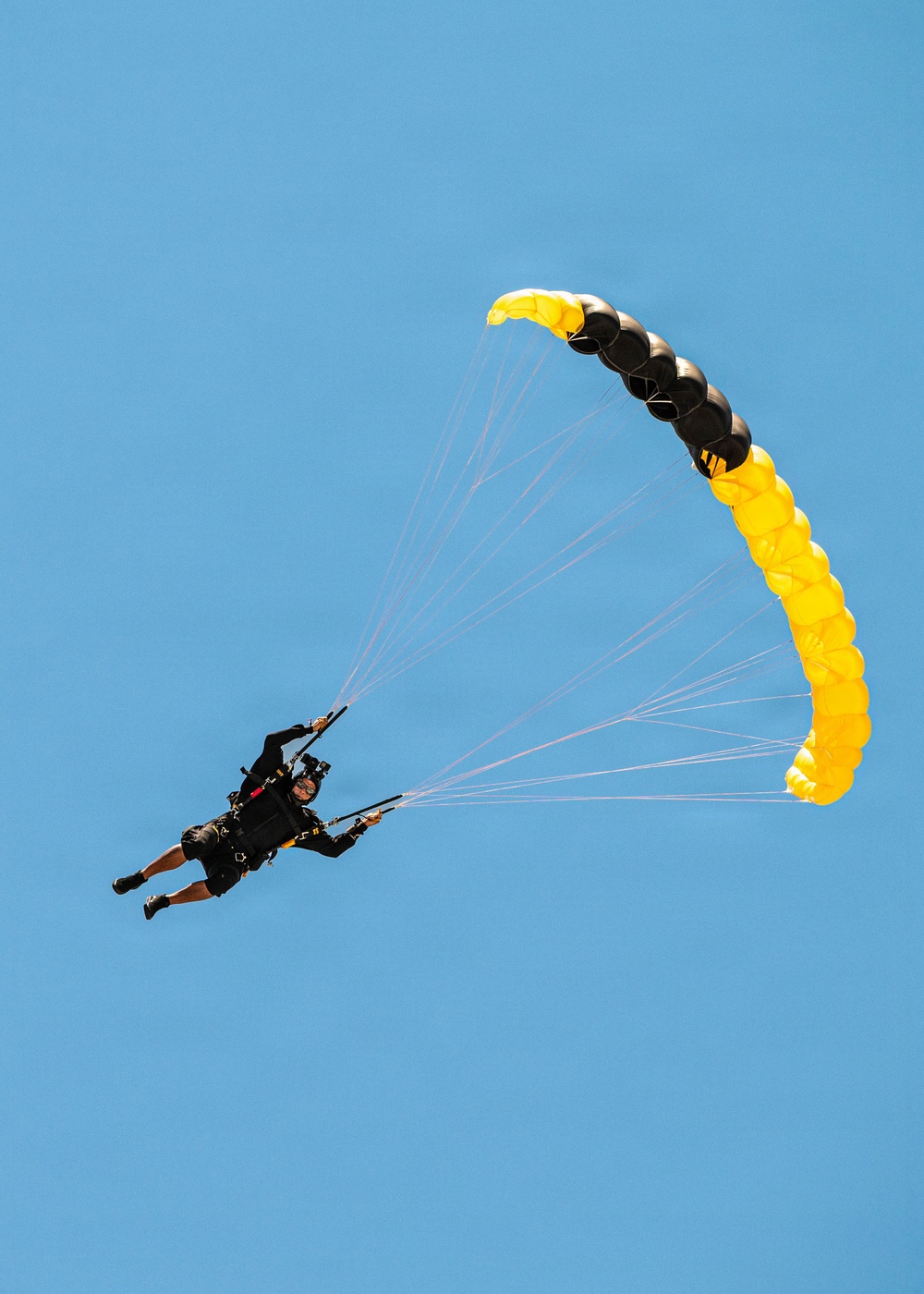 U.S. Army Golden Knights parachutist descends under black and gold canopy during Hyundai Air and Sea Show