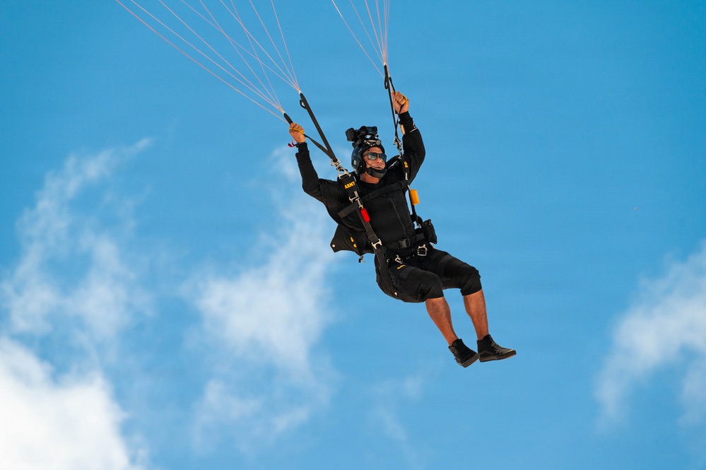 U.S. Army Golden Knights parachutist descends under black and gold canopy during Hyundai Air and Sea Show.
