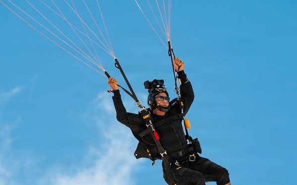 U.S. Army Golden Knights parachutist descends under black and gold canopy during Hyundai Air and Sea Show.