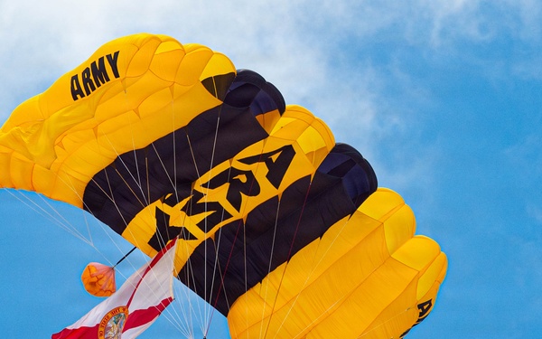 U.S. Army Golden Knights parachutist carries Florida state flag during aerial demonstration at Miami Beach
