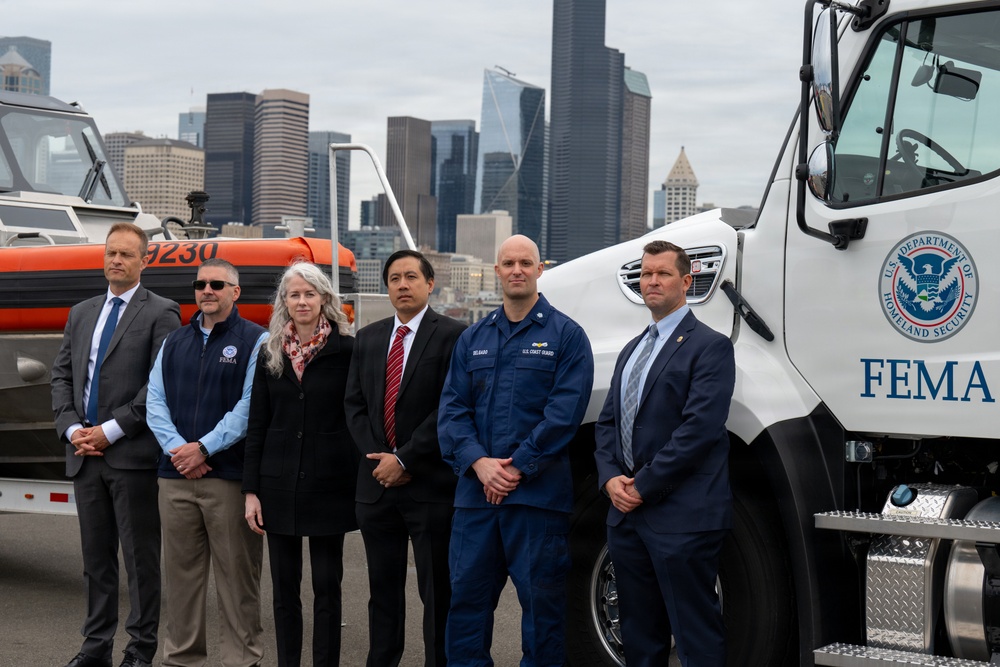 federal, state, and local agency partners pose for a group photo during a media event at Coast Guard Base Seattle.