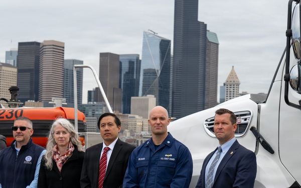federal, state, and local agency partners pose for a group photo during a media event at Coast Guard Base Seattle.