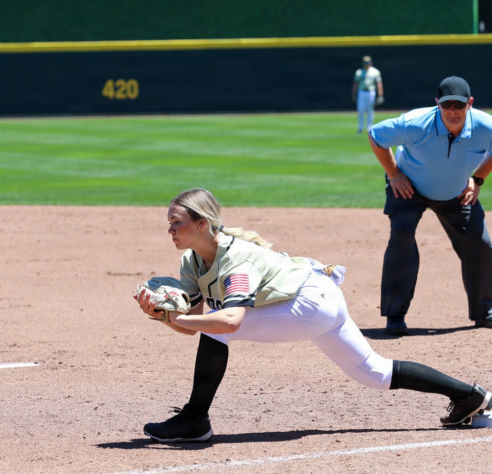 Military-themed softball player stretches to make catch at first base during game