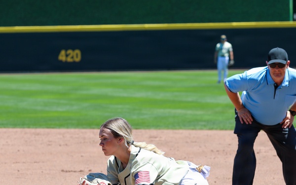 Military-themed softball player stretches to make catch at first base during game