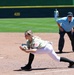 Military-themed softball player stretches to make catch at first base during game